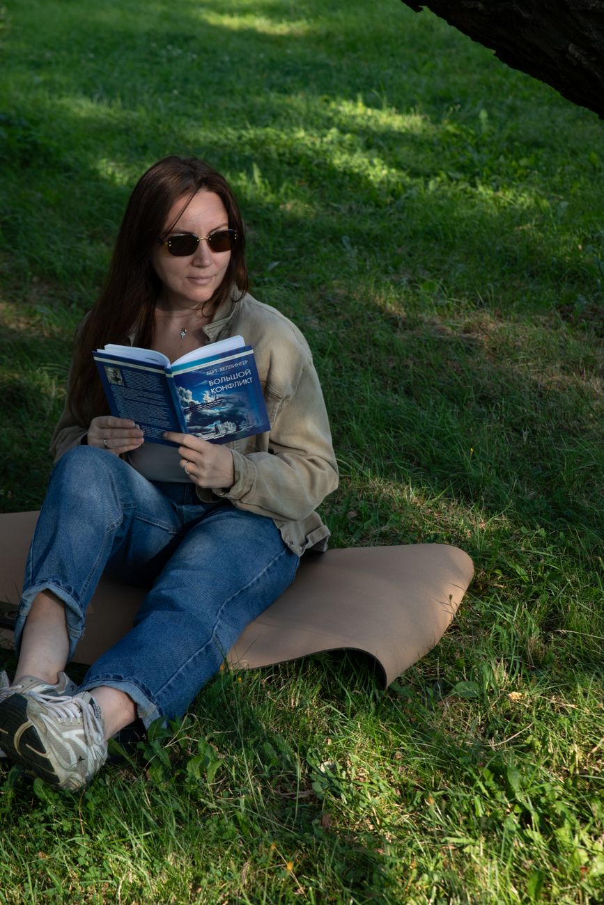 Woman reading a book on the grass in a park